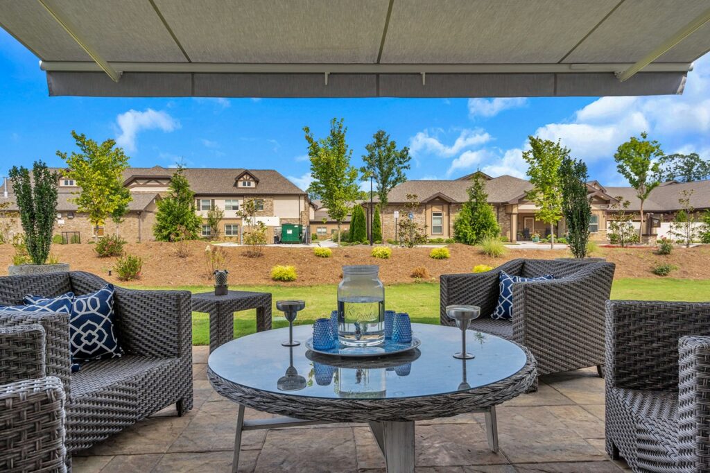 A photo of the large cottage's patio with a coffee table and sitting chairs, overlooking a nature landscape and other cottages at Celebration Village Forsyth, a senior living community near Alpharetta, GA.