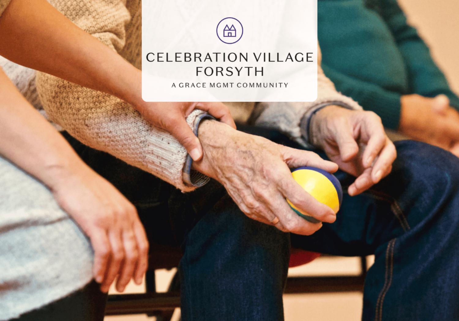 Seniors seated together, hands on a yellow and blue ball, illustrating a social activity at Celebration Village Forsyth.